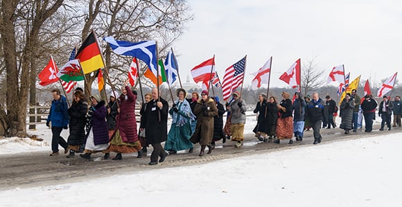 Members and missionaries walk down Main and Parley Streets in Nauvoo on February 2, 2019, to commemorate the 1846 Nauvoo Exodus. The flags represent many of the nationalities of those who lived in Nauvoo in the 1840s. Photo courtesy of Bruce Cornwel…